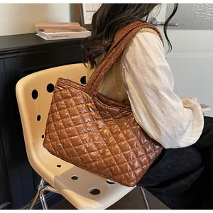 Detail of brown quilted puffer tote bag featuring classic diamond stitching and wide straps