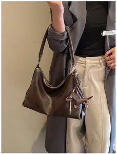 Détail du sac à bandoulière en cuir marron avec breloques de teckel et chocolat