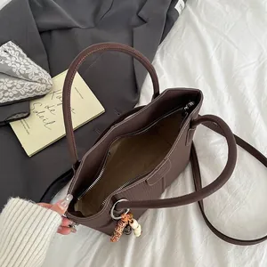 Dunkelbraune Eimertasche mit feiner vertikaler Textur und Vintage-Perlenanhänger