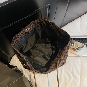 Spacious leopard print tote bag with brown straps shown on bed with lifestyle items