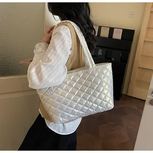 Close-up of a silver quilted puffer tote bag with metallic finish shown on model