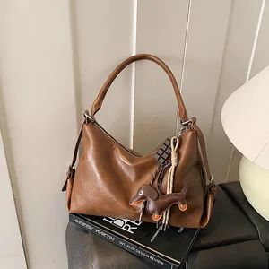 Sac sous le bras vintage en cuir marron avec charme de chien sur une pile de livres