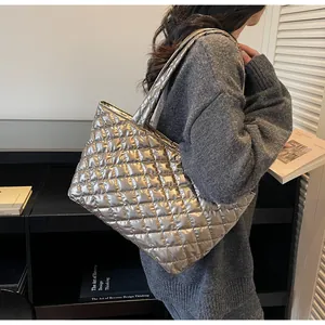 Silver metallic puffer tote bag with quilted texture shown on shoulder with wide strap