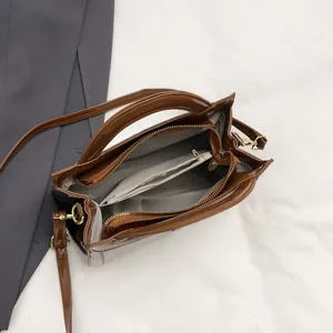 Glossy brown top handle bag with crossbody strap and organized interior compartments