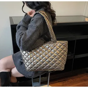 Detail of silver quilted tote bag with metallic finish shown on model in studio
