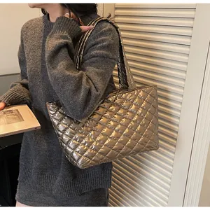 Detailed side view of a large quilted metallic tote bag worn over the shoulder