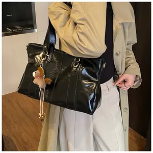 Detail einer schwarzen Kunstleder-Tote-Bag mit Glanzeffekt und braunem Pferdeanhänger