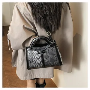 Detailed close-up of snakeskin texture handbag with glossy leather trim and metal logo