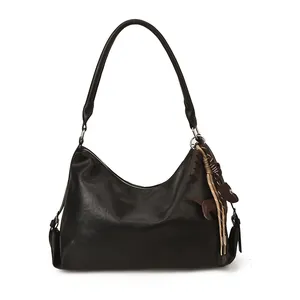 Sac hobo rétro en cuir noir avec un charmant pendentif chien brun sur un fond blanc pur