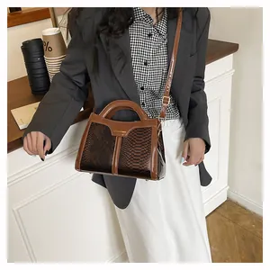 Detail of a brown snakeskin pattern tote bag with gold hardware on a cafe counter