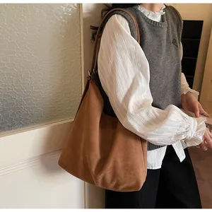 Brown faux suede hobo bag shown on shoulder with minimalist vintage bucket style