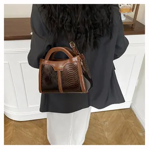 Detailed view of the dark brown snake pattern embossed handbag with gold metal logo