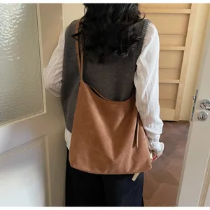 Brown faux suede hobo bag shown on shoulder in a warm lifestyle indoor setting