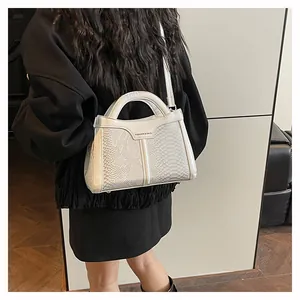 Detail of white snake-embossed trapezoid handbag with dual handles and fashion logo