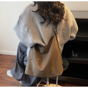 Detail of dark brown suede shoulder bag with adjustable strap worn in a cozy room