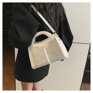 Detailed view of white snakeskin pattern on a handbag with elegant gold metal hardware