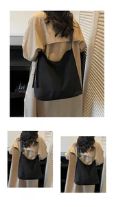 Detail of a large black soft suede shoulder bag worn with a casual brown trench coat