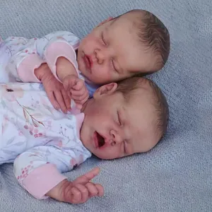 Gemelli reborn da 18 pollici in tutine a fiori su una coperta di maglia grigia