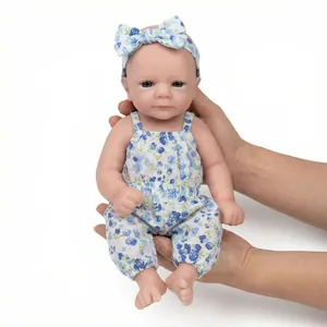 Lifelike 12-inch reborn doll in blue floral romper held in hands on white background