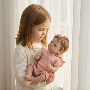 Bambola reborn realistica da 18 pollici in pagliaccetto rosa tenuta da un bambino