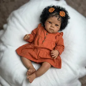 Poupée Reborn réaliste de 18 pouces avec cheveux bouclés et robe orange sur oreiller