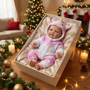 17-inch realistic reborn doll in unicorn onesie lying in a gift box by Christmas tree