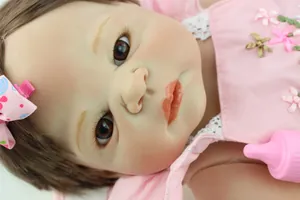 Detailopname van levensechte babypop met handgeschilderde wenkbrauwen en roze jurk