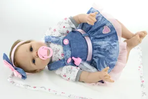 Detailed set of reborn baby doll with denim dress, pacifier, and feeding bottle