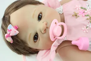 Detailopname van realistische babypop met bruin haar, roze jurk en accessoires