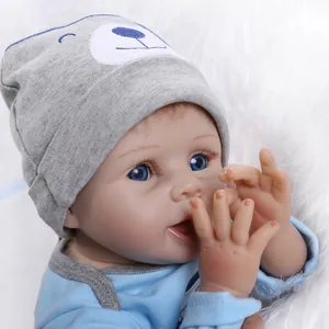 Lifelike reborn baby doll in blue romper and grey bear hat on white plush rug