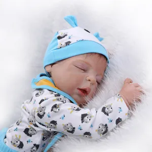 Realistische Reborn-Babypuppe im blauen Esel-Outfit schlafend auf weißem Plüschteppich