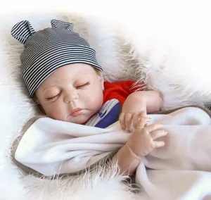 Gros plan d'une poupée reborn endormie avec bonnet rayé et chemise rouge sur fourrure blanche