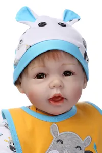 Dettaglio di una bambola reborn realistica con cappello animale e bavaglio giallo