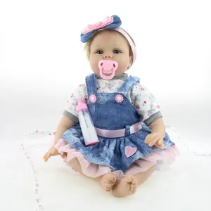 Realistic reborn baby doll in floral shirt and denim dress with pacifier and bottle