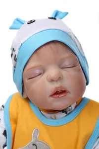 Nahaufnahme einer schlafenden Silikon-Babypuppe mit blau gemusterter Mütze und gelber Weste