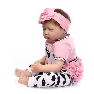 Realistic reborn baby doll in pink floral headband sleeping in a seated position