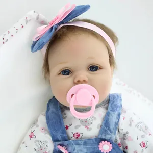 Lifelike reborn baby doll with blue eyes, floral top and blue denim overalls set