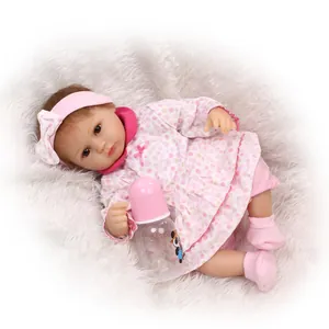 Realistic reborn baby doll in pink floral dress with bottle on white fur rug
