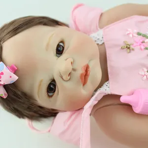Realistische Reborn-babypop in roze kanten jurk met bruin haar en babyflesje