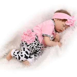 Detailed view of sleeping reborn baby doll in pink floral headband and cow print pants