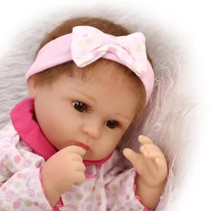 Realistic reborn baby doll in pink polka dot outfit with matching headband on soft plush