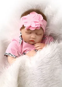 Close-up of sleeping reborn doll in pink outfit on soft white plush background