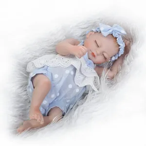 Sleeping realistic baby doll in blue polka dot outfit on white faux fur background