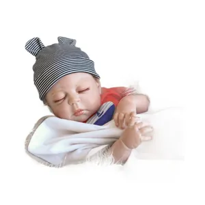 Poupée bébé reborn réaliste endormie avec bonnet rayé et chemise rouge sur fond blanc