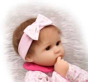 Close-up of lifelike reborn baby doll with pink polka dot outfit and soft brown hair