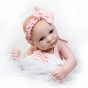 Realistic reborn baby doll in pink polka dot outfit on white faux fur background