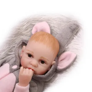 Lifelike reborn baby doll in pink elephant plush onesie on white faux fur background