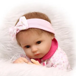 Realistic reborn baby doll in pink polka dot outfit resting on soft white faux fur