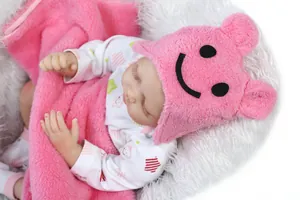 Close-up of lifelike reborn baby doll in polka dot outfit with pink plush hat and blanket