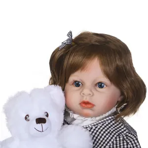 Realistic reborn toddler girl doll with blue eyes, brown hair and a plush teddy bear